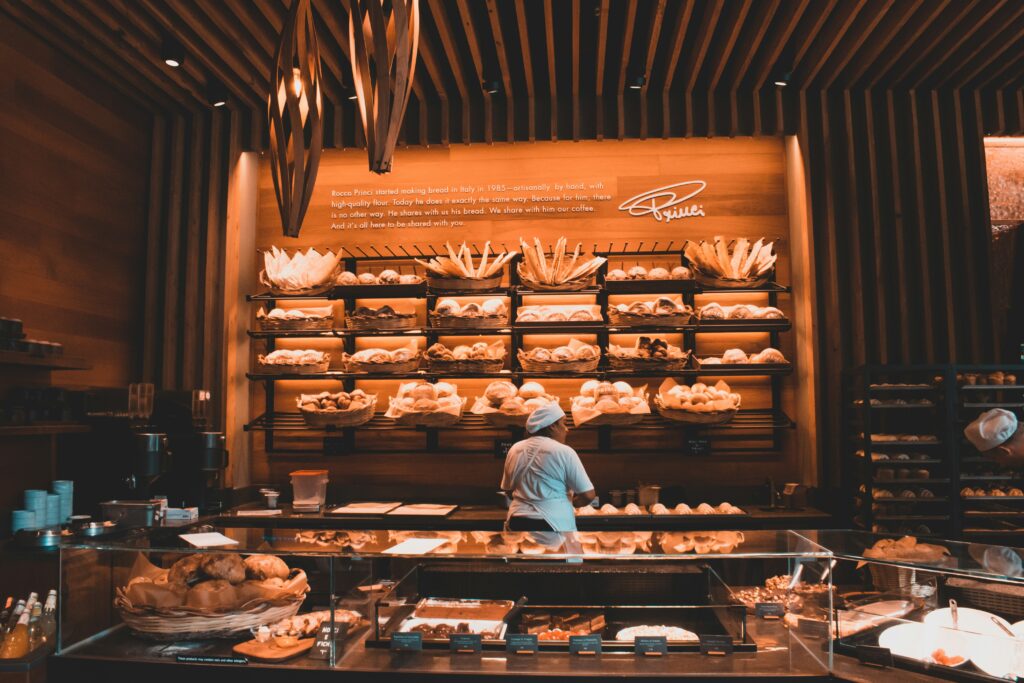 A charming local bakery filled with freshly baked goods, showcasing an array of pastries, bread, and cakes, while customers enjoy treats at cozy seating areas.